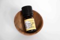 Rumianek rzymski organiczny olejek eteryczny Ekome® 5 ml - buteleczka w drewnianej miseczce na jasnym tle