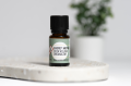 Cedr atlaski organiczny olejek eteryczny 10 ml Ekome®, butelka na jasnej podstawce z rośliną w tle