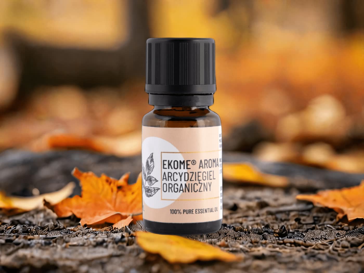 Butelka olejku Ekome Aroma Arcydzięgiel Organiczny na tle jesiennych liści.