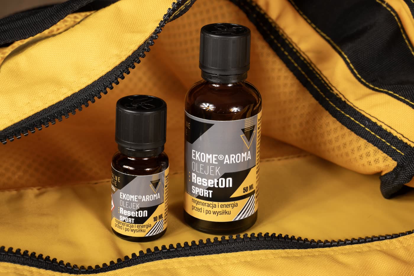 Butelki olejku Ekome® Aroma ResetON Sport 10 ml i 50 ml w sportowej torbie. Naturalny olejek do masażu wspierający regenerację i energię przed i po wysiłku fizycznym. Produkt aromaterapeutyczny dla osób aktywnych.