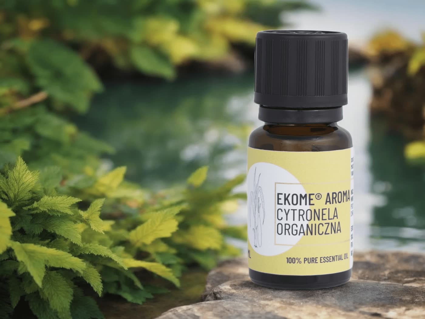 Zdjęcie pokazuje butelkę z olejkiem eterycznym "Cytronela Organiczna" marki Ekome, ustawioną na kamiennej powierzchni z roślinnością i wodą w tle. Naturalne otoczenie, w tym zielone liście i spokojna woda, podkreślają organiczny charakter produktu. Butelka jest umieszczona w centralnym punkcie obrazu, z widoczną etykietą, na której znajduje się nazwa produktu i marki. Całość kompozycji sugeruje, że produkt jest częścią ekologicznego i zrównoważonego stylu życia.