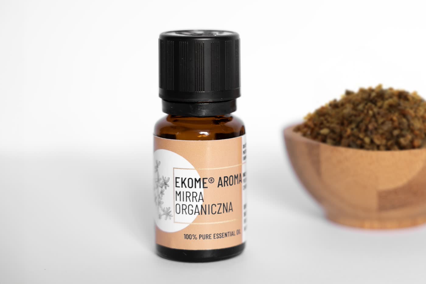 Butelka olejku Ekome Aroma Mirra Organiczna na bia%u0142ym tle obok miseczki z %u017Cywic%u0105 mirry.