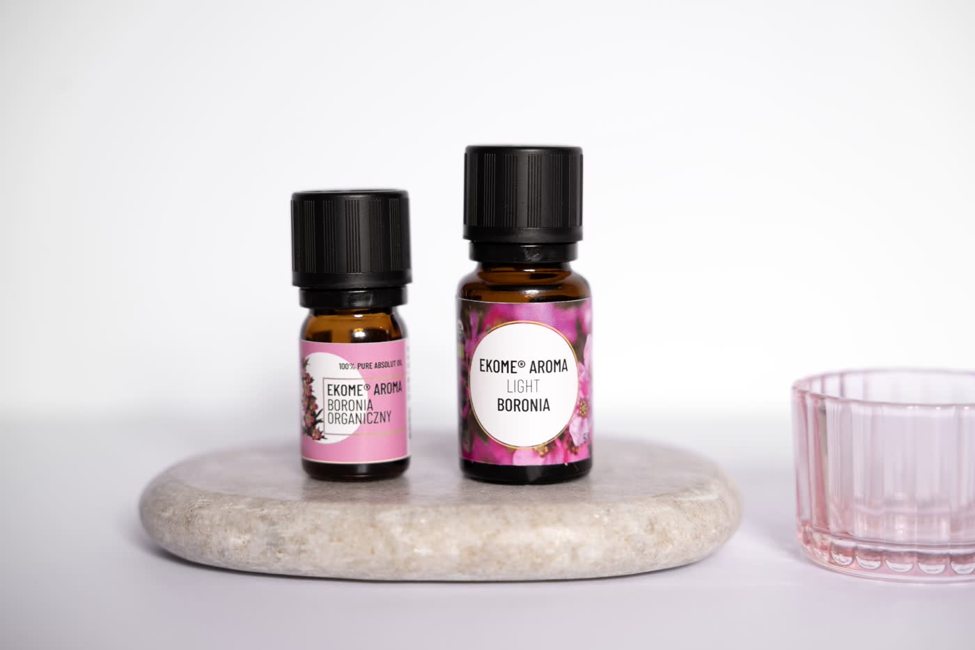 Dwa flakoniki organicznych olejków Ekome® Aroma Boronia: Boronia Organiczny i Light Boronia, ustawione na kamiennej podstawce, na jasnym tle.