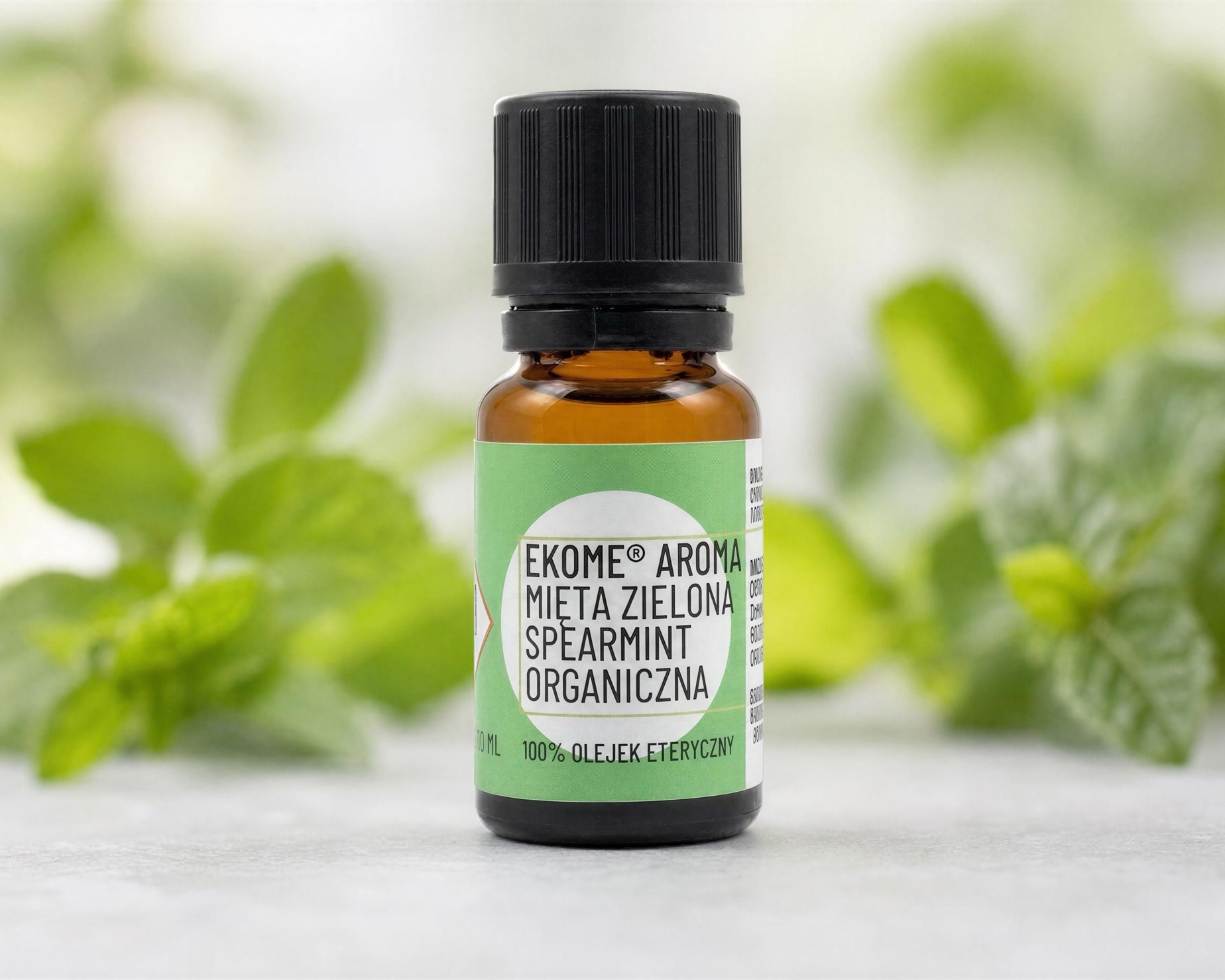 Mięta zielona Spearmint organiczny olejek eteryczny 10 ml Ekome® - buteleczka z liśćmi mięty Organiczny olejek eteryczny Mięta zielona Spearmint Ekome® 10 ml z liśćmi mięty w tle